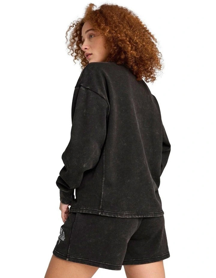 Person wearing a black hoodie and shorts set with visible branding on a white background