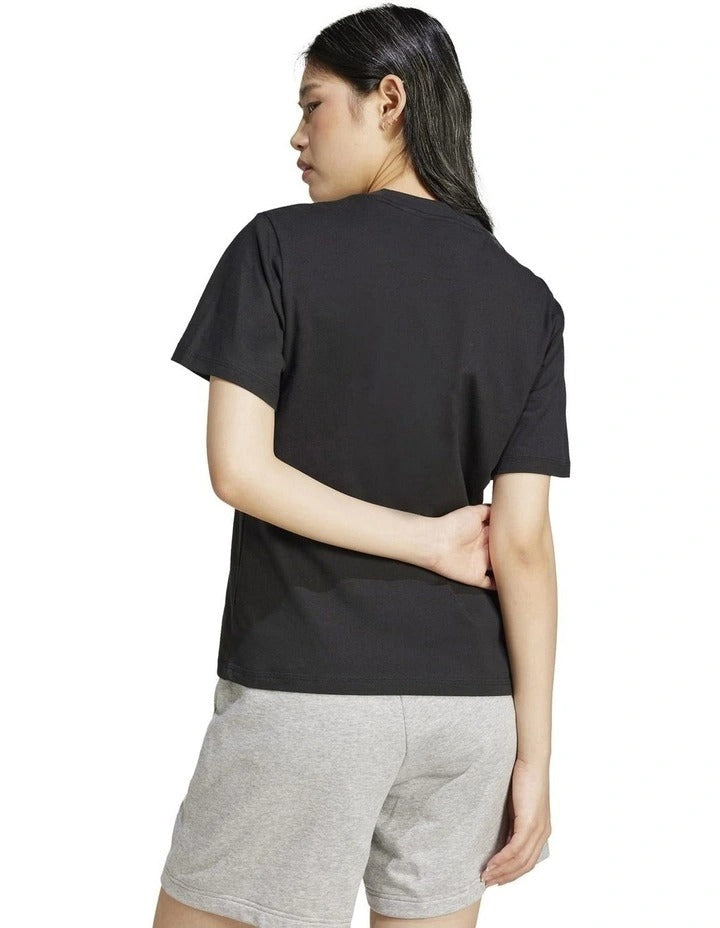 Person wearing a black Adidas t-shirt on a white background