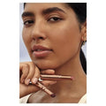 Woman holding a rose gold lipstick with a blurred background