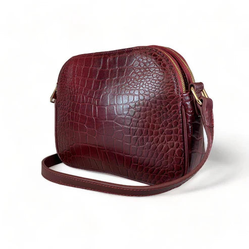 Dark red crocodile-embossed leather shoulder bag with gold hardware and adjustable crossbody strap, luxury women’s handbag on white background.