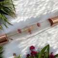 Lavvish Rose Quartz Facial Roller with box displayed on iridescent stand surrounded by small potted succulents