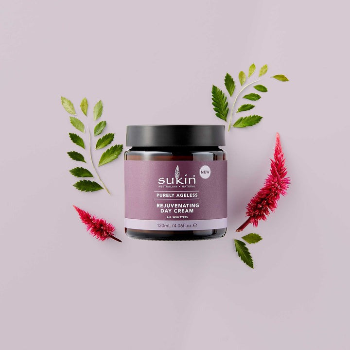 Sukin skincare jar with pink flowers and green leaves on a light purple background