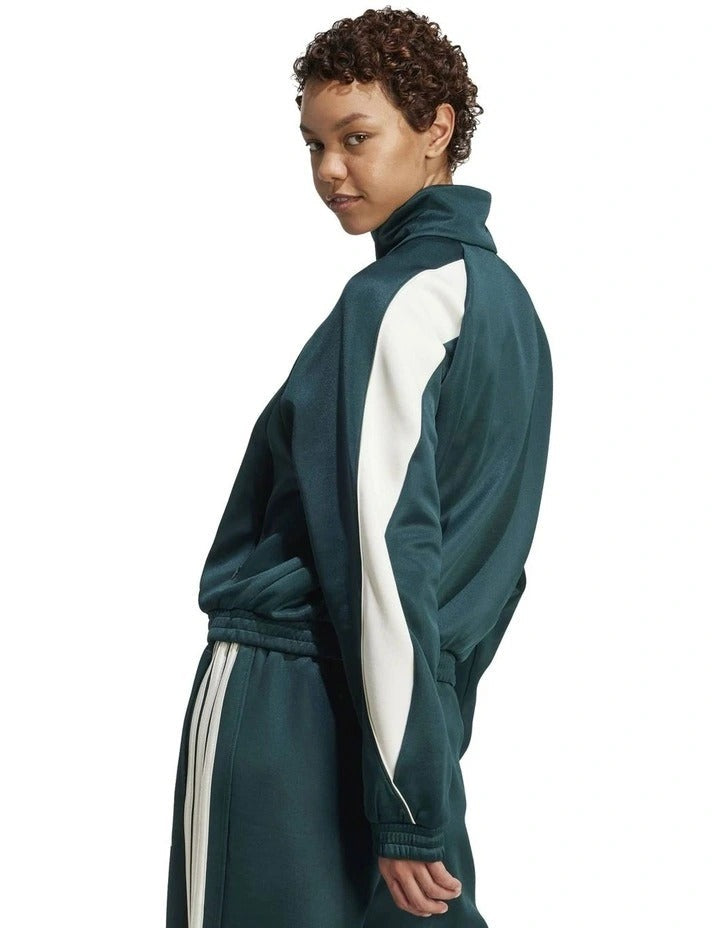 Person wearing a green Adidas tracksuit on a white background