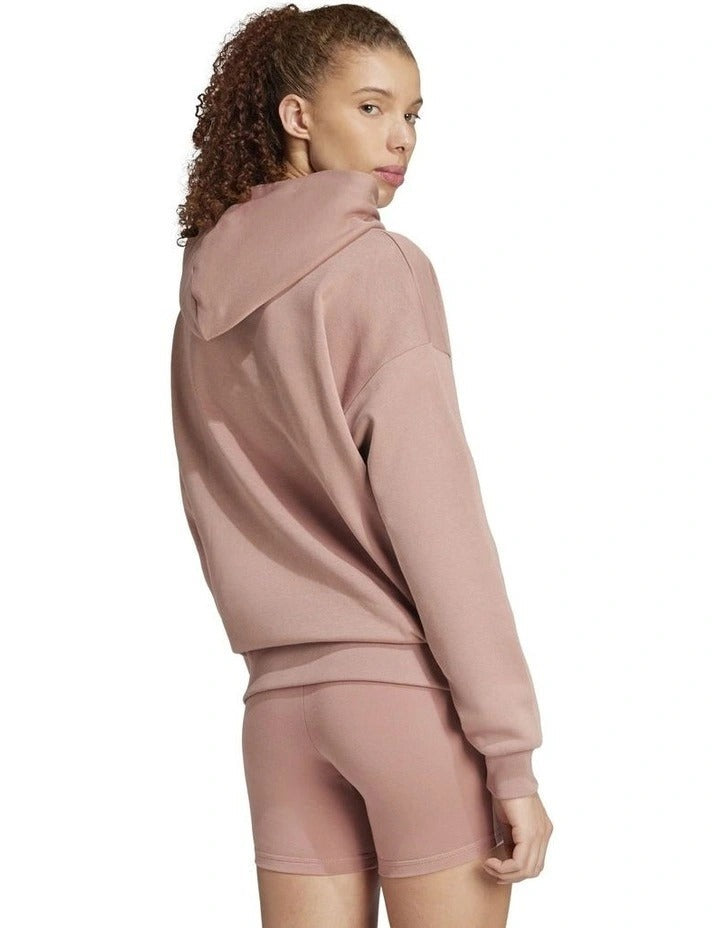 Woman wearing a pink Adidas hoodie and shorts on a white background