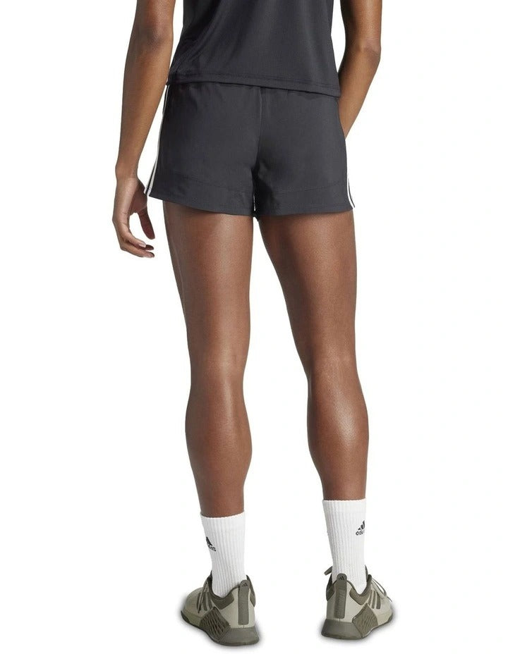 Person wearing black Adidas shorts with white stripes on a white background