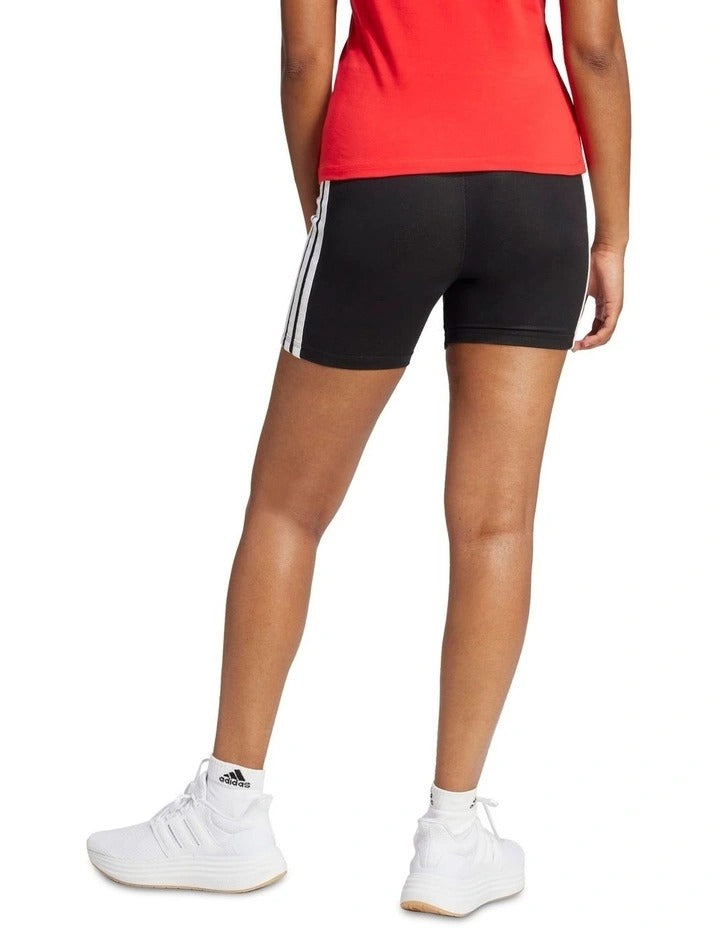 Person wearing black Adidas shorts with white stripes on a white background