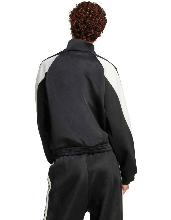 Person wearing a black Adidas tracksuit on a white background