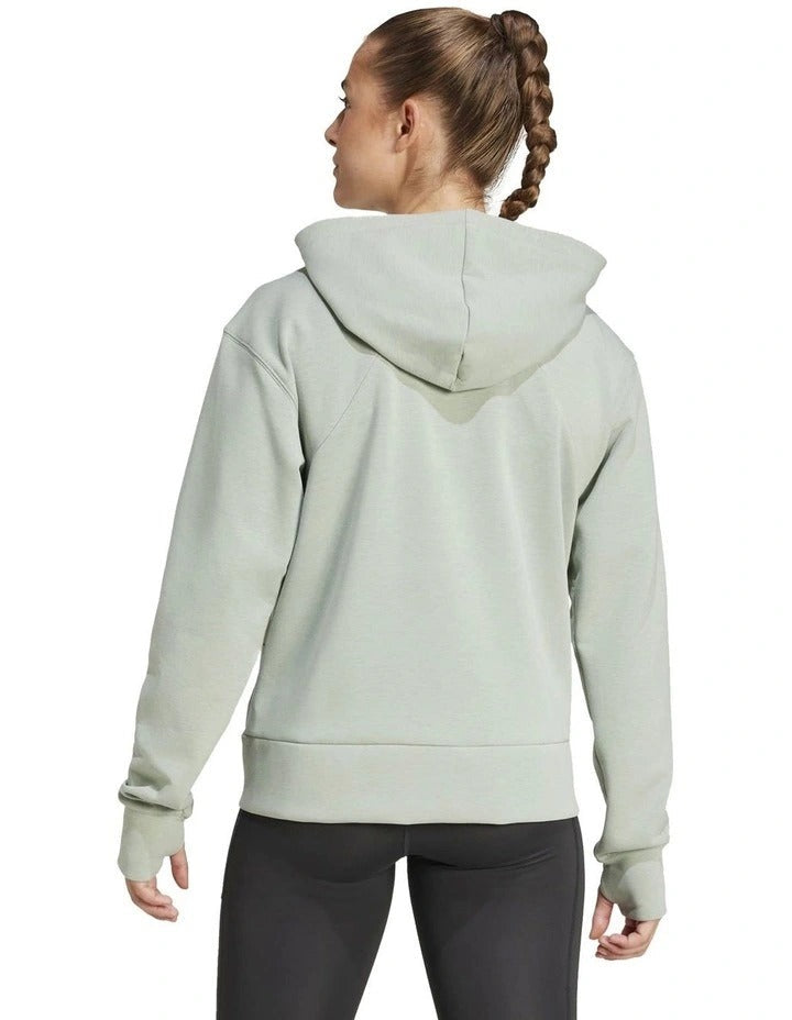 Woman wearing a light gray Adidas hoodie on a white background