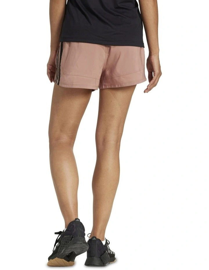 Person wearing pink Adidas shorts on a white background