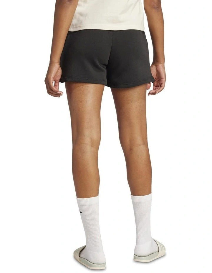 Person wearing black Adidas shorts on a white background
